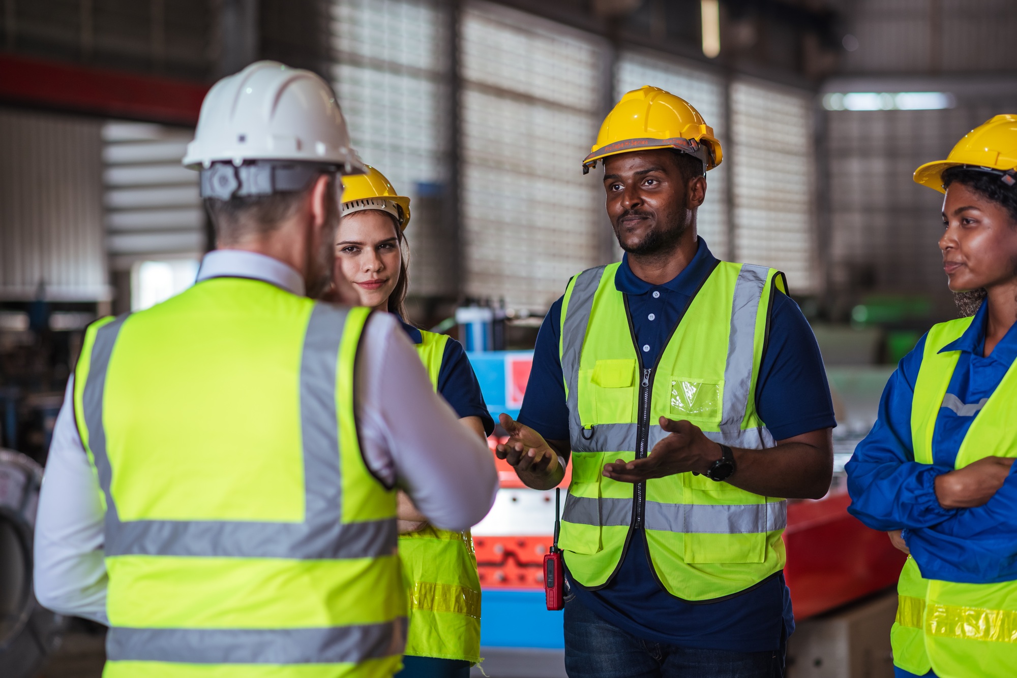 Diverse factory team standing in warehouse for production meeting focused on safety compliance
