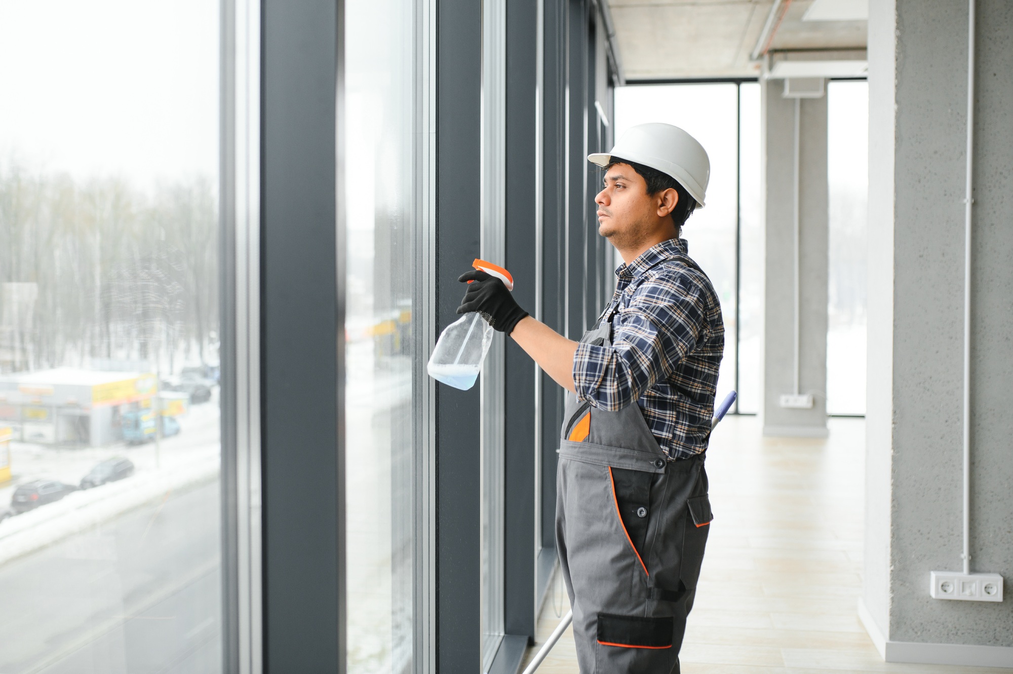 Male janitor cleaning window in office